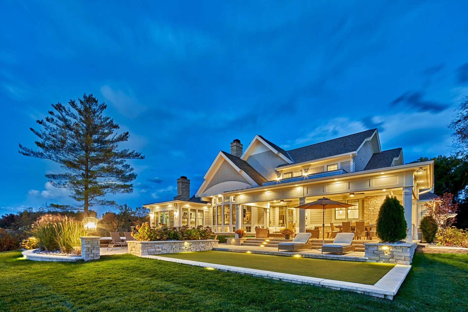 Lit grounds, walkways and planting on a large property at dusk