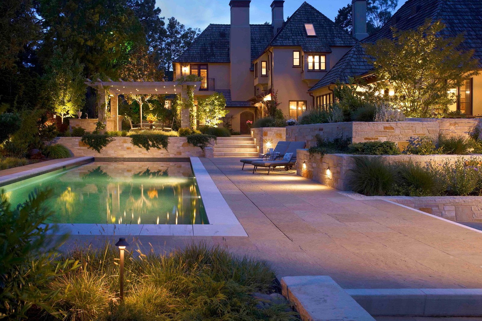 A pool at night with lit coping, surround and planting